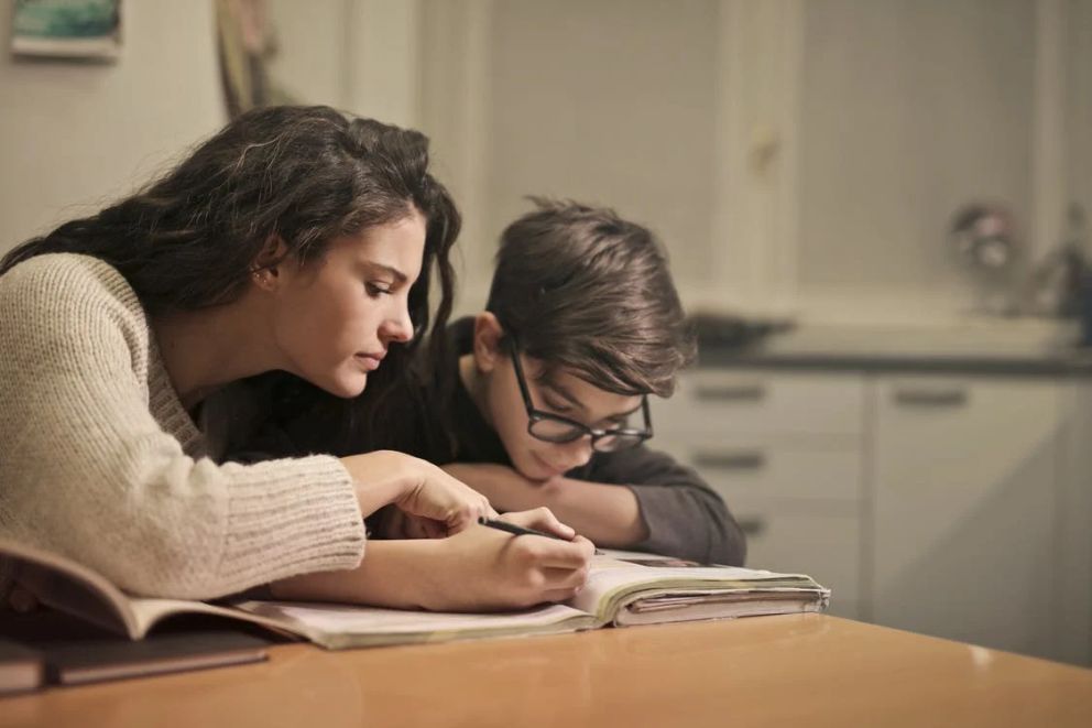 Una mujer ayudando a un niño con su tarea. | Foto: Pexels