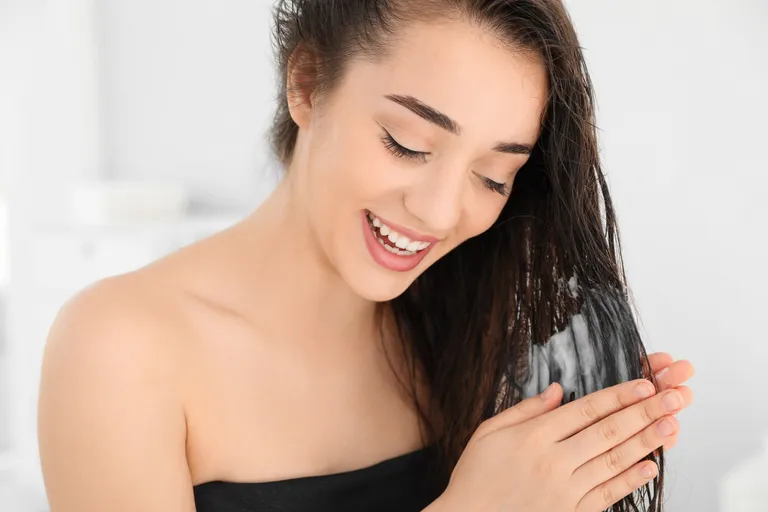 Mujer aplicando mascarilla en su cabello. | Foto: Shutterstock