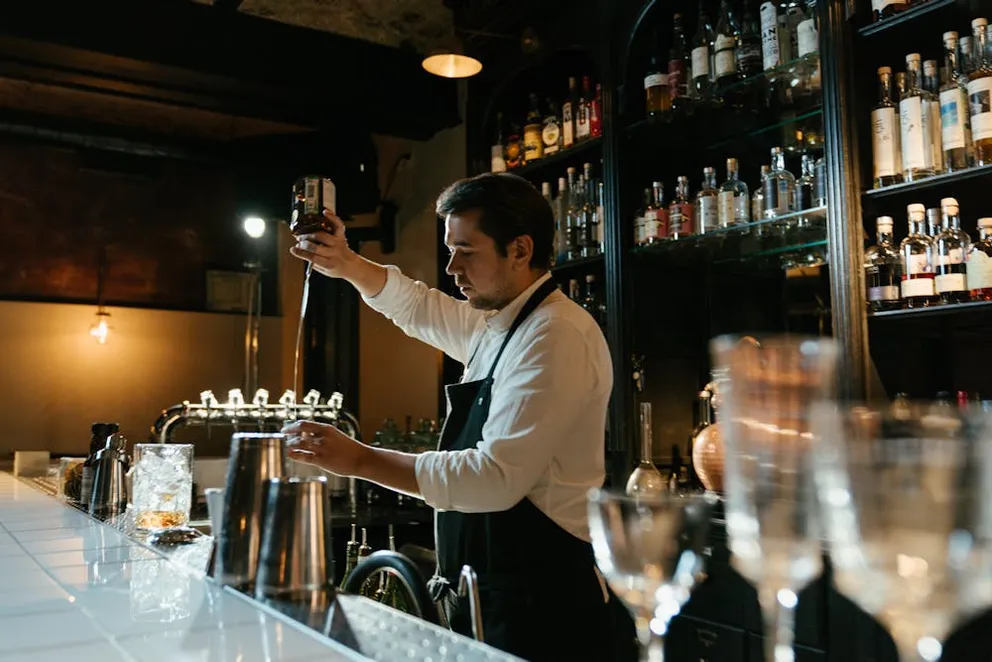 Bartender pouring a drink into a glass | Photo: Pexels