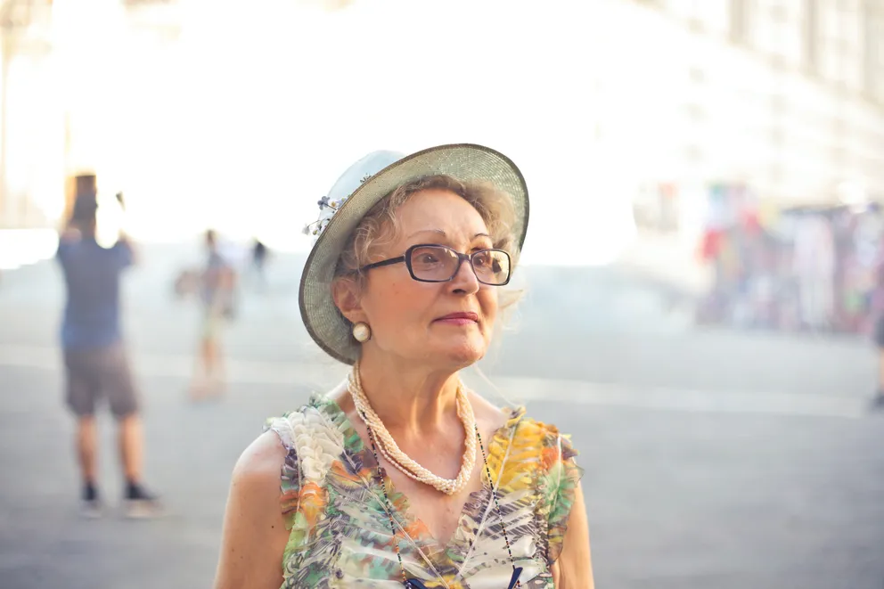 Una mujer mayor en un lugar abierto con gente alrededor. | Foto: Pexels