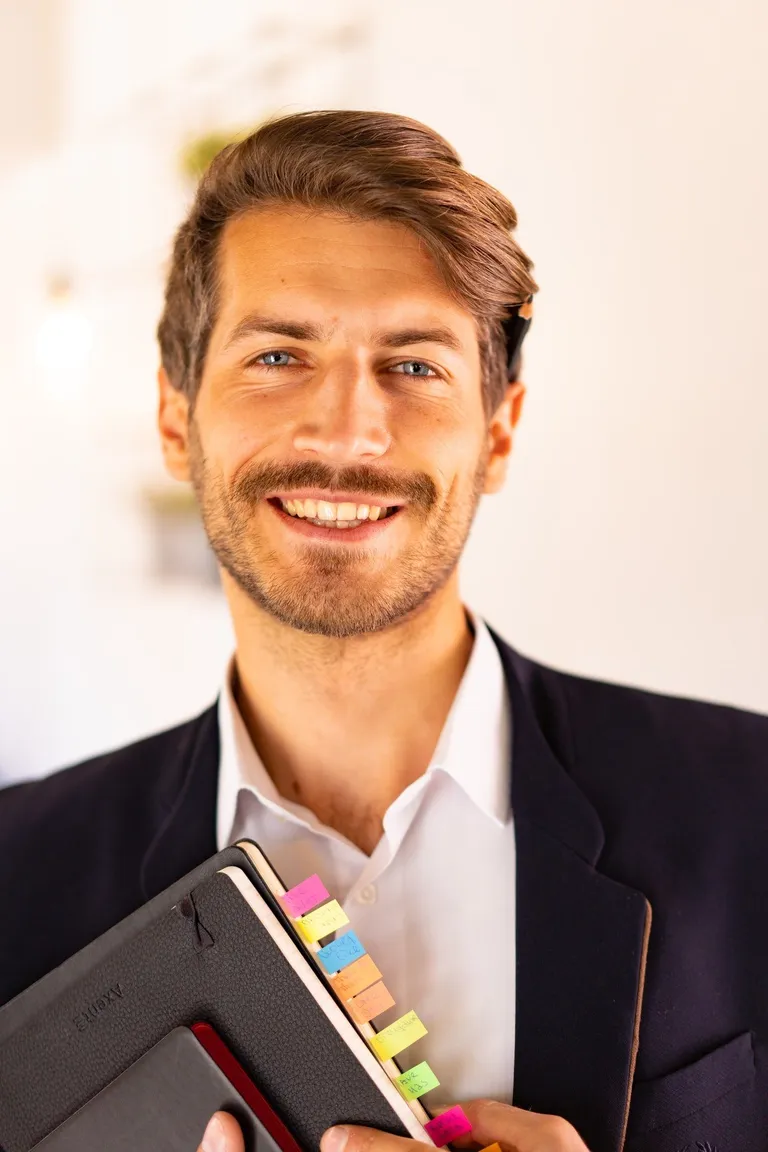 Hombre con corbata sosteniendo una libreta. | Foto: Pexels