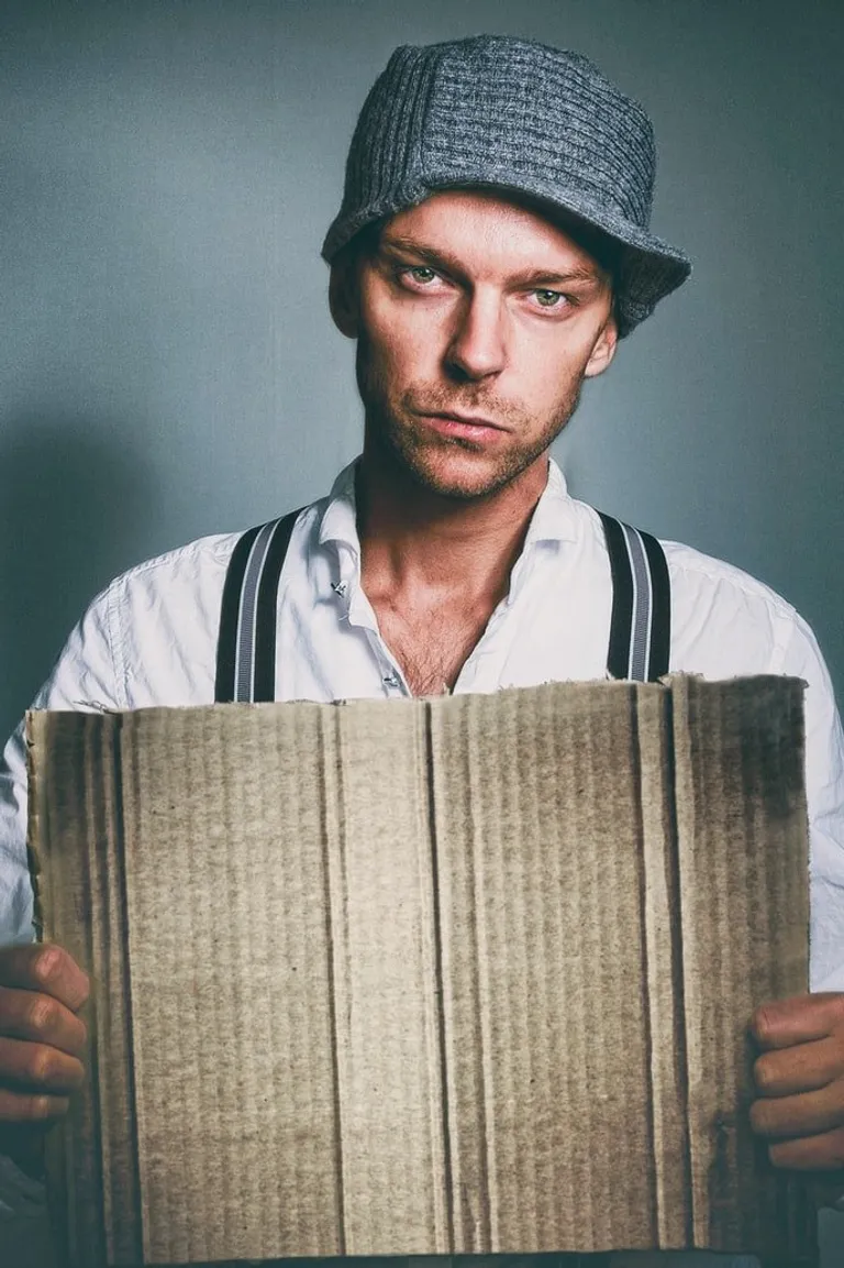 Un hombre con rostro serio sosteniendo un cartón. | Foto: Unsplash