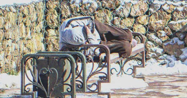 Hombre sin hogar recostado en un banquillo. | Foto: Shutterstock