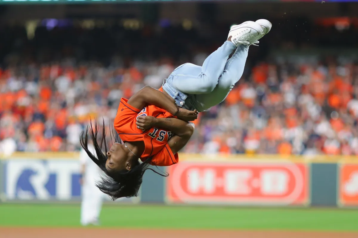 Simone Biles flips before throwing out the first pitch prior to Game 2 of the 2019 World Series on Wednesday, October 23, 2019 in Texas. | Photo: Getty Images