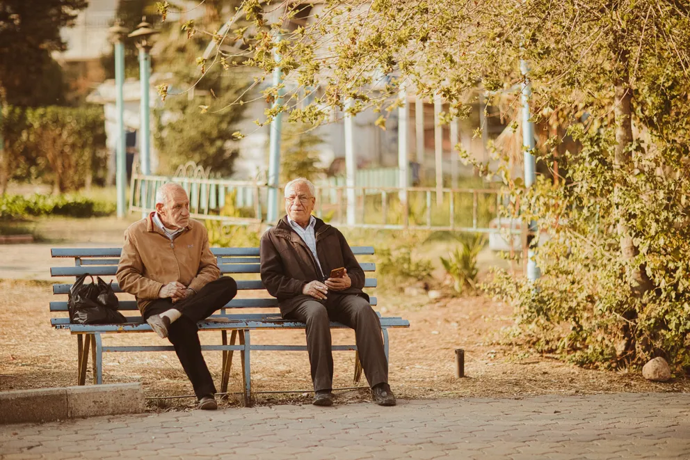 Dos hombres mayores sentados en el banquillo de un parque. | Foto: Pexels