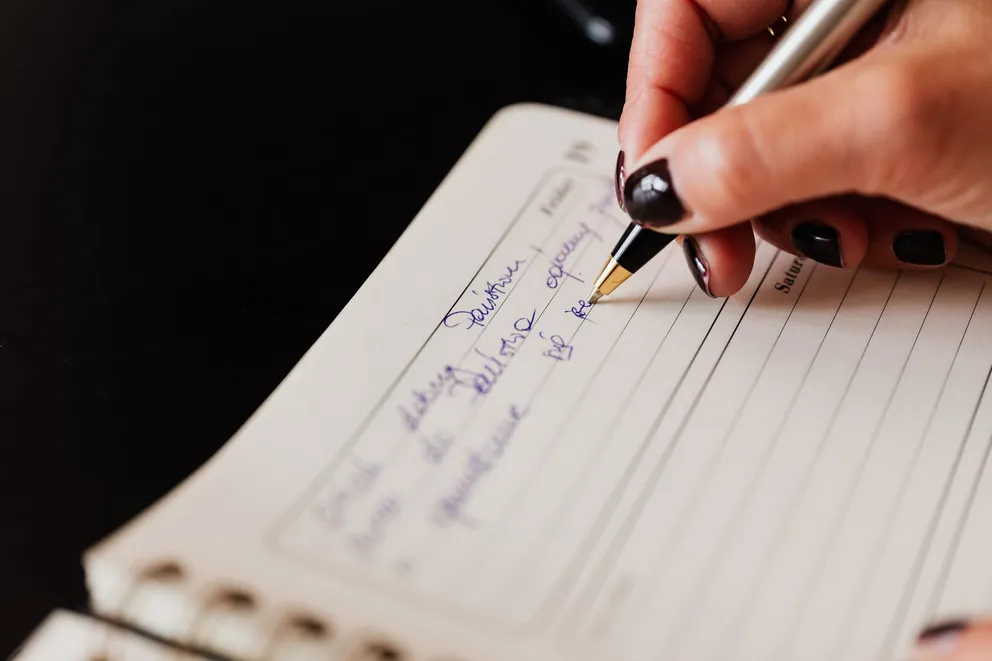 Una mujer escribiendo con un bolígrafo en un cuaderno. | Foto: Pexels