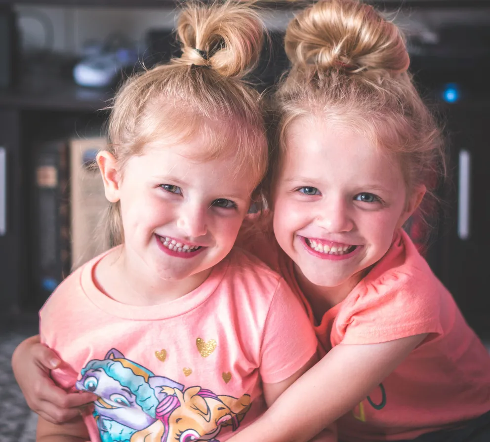 Dos niñas sonriendo mientras se abrazan. | Foto: Pexels