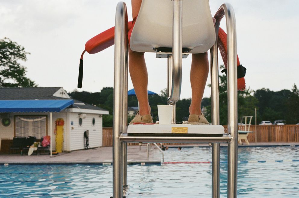 Un socorrista sentado en su silla en una piscina. | Foto: Unsplash