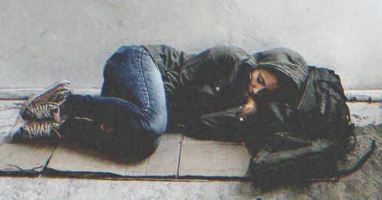 Mujer sin hogar recostada sobre un cartón en el suelo. | Foto: Shutterstock