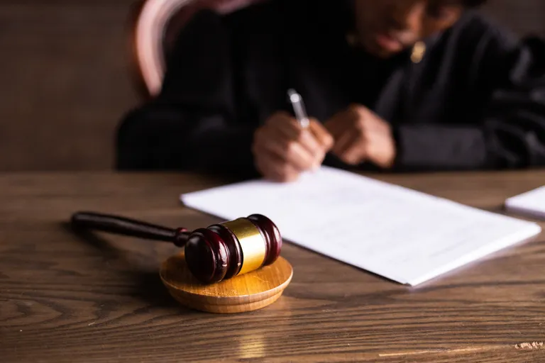 Un juez escribiendo en unas hojas con su martillo a un lado. | Foto: Pexels
