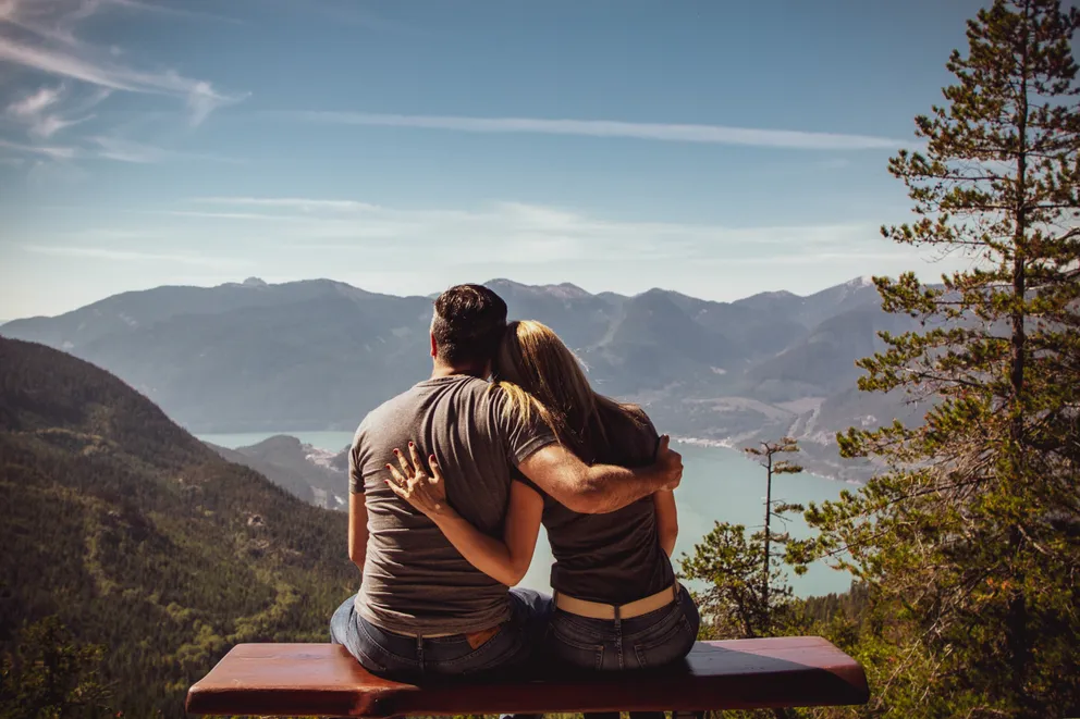 Una pareja abrazada mirando un paisaje montañoso. | Foto: Pexels