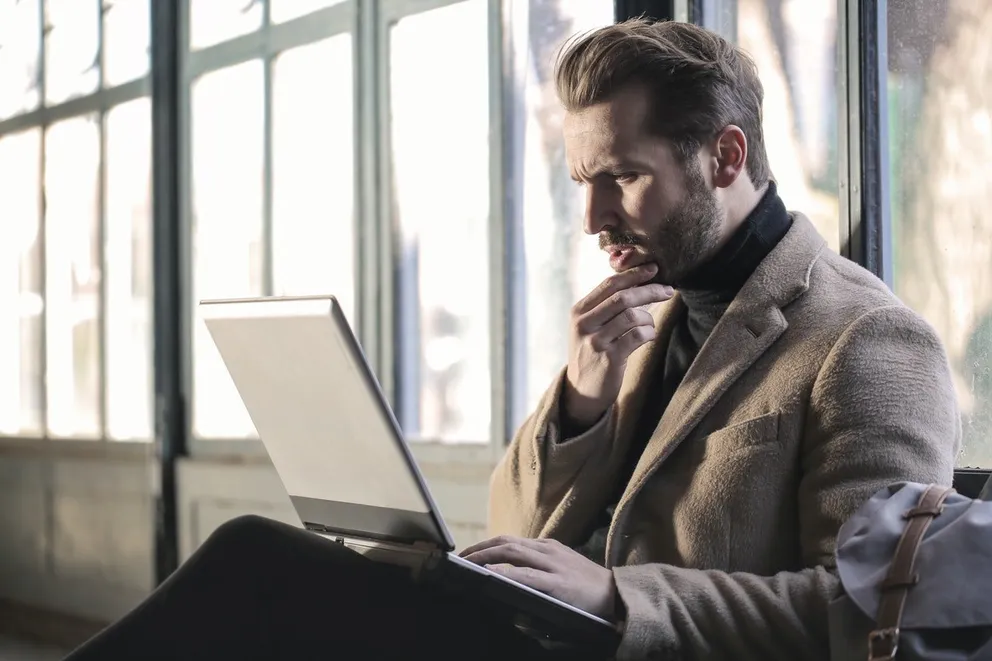 Un hombre sentado con una computadora portátil sobre su regazo. | Foto: Pexels