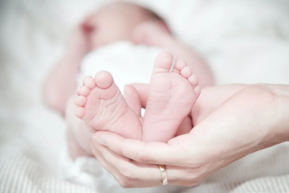 Mujer sosteniendo los pies de un bebé. | Foto: Pexels