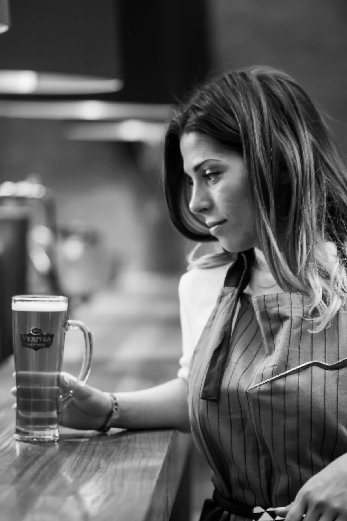 Une femme assise au comptoir d'un bar tenant un verre de bière | Photo : Pixabay