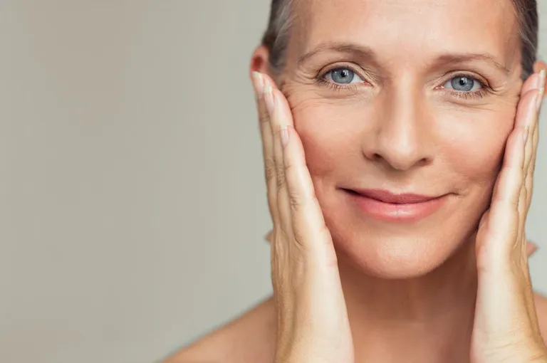 Bella mujer madura tocando su piel perfecta y mirando la cámara. | Foto: Shutterstock