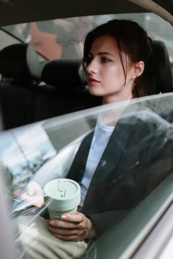 Mujer sentada en el asiento trasero de un vehículo sosteniendo un vaso. | Foto: Pexels