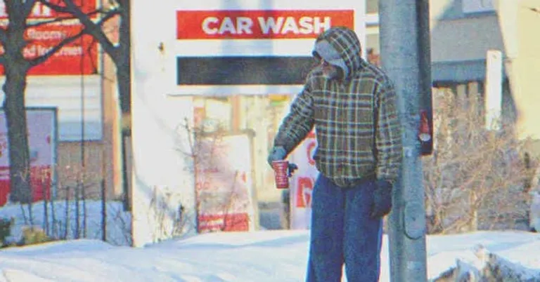 Un hombre sin hogar recostado de un poste. | Foto: Shutterstock