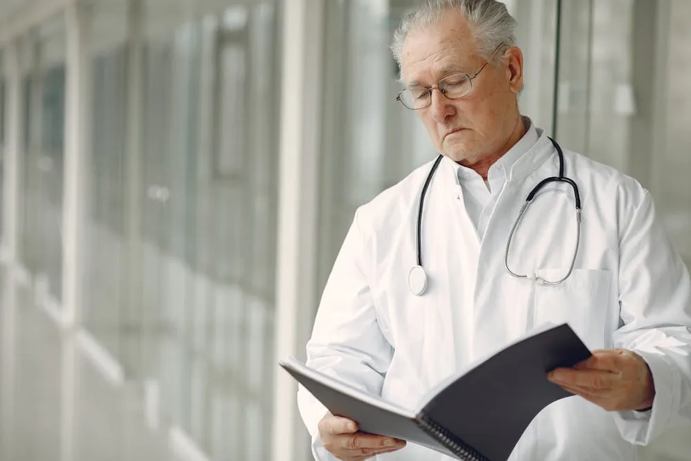 A doctor in uniform reading clinical records. | Photo: Pexels