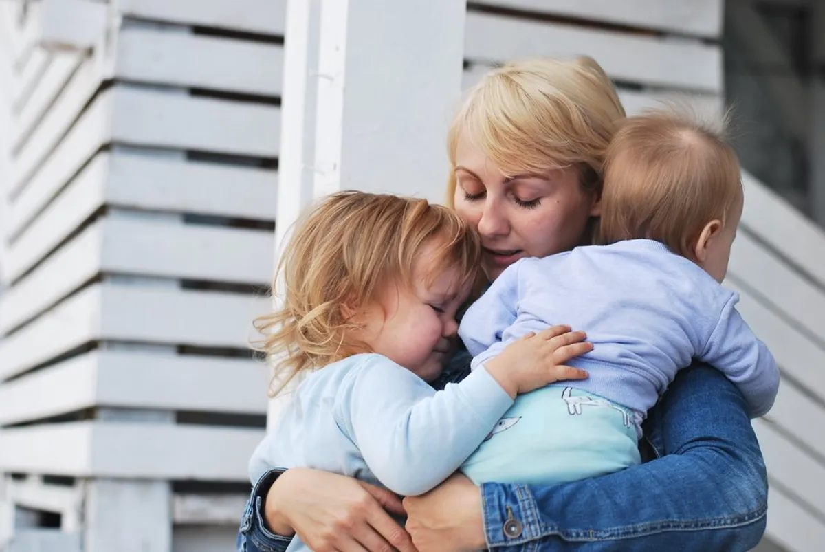 Eine traurige Frau mit zwei Kindern im Arm. | Quelle: Shutterstock