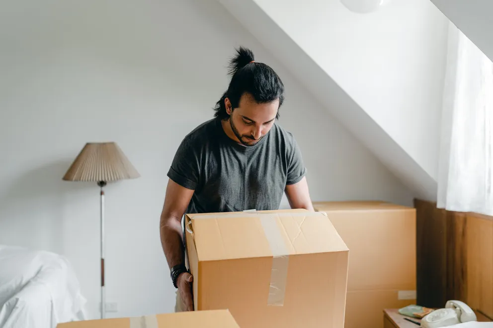Hombre moviendo unas cajas en una habitación. | Foto: Pexels
