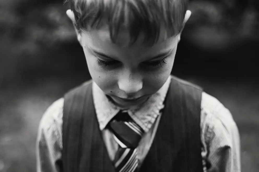 Un niño mirando hacia el suelo. | Foto: Pexels