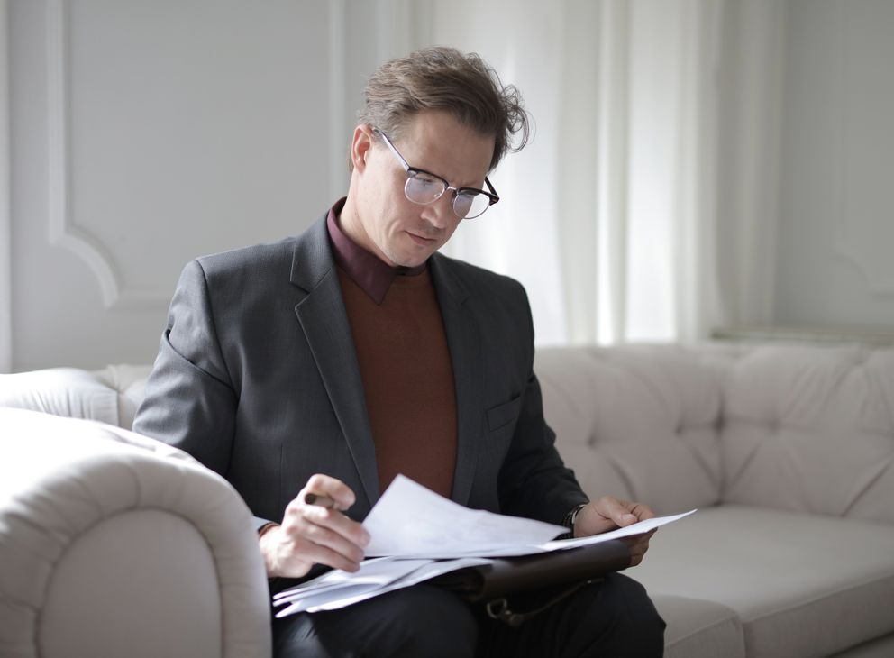 Un hombre sentado en un sofá revisando unos documentos. | Foto: Pexels