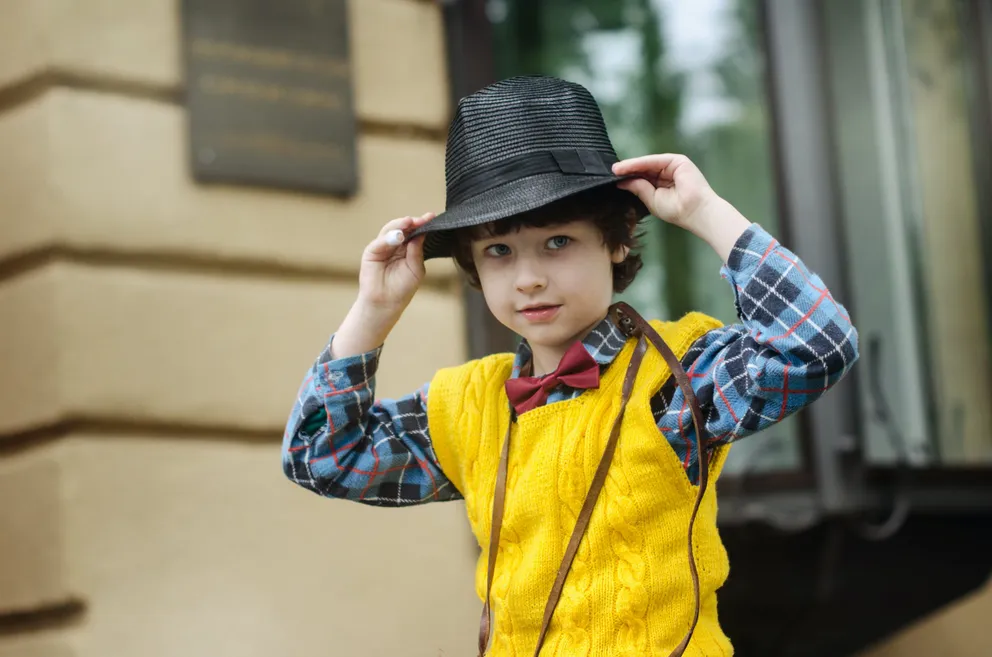 Niño frente a una casa usando un sombrero. | Foto: Pexels