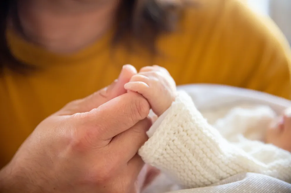 Una persona sosteniendo la mano de un bebé. | Foto: Pexels