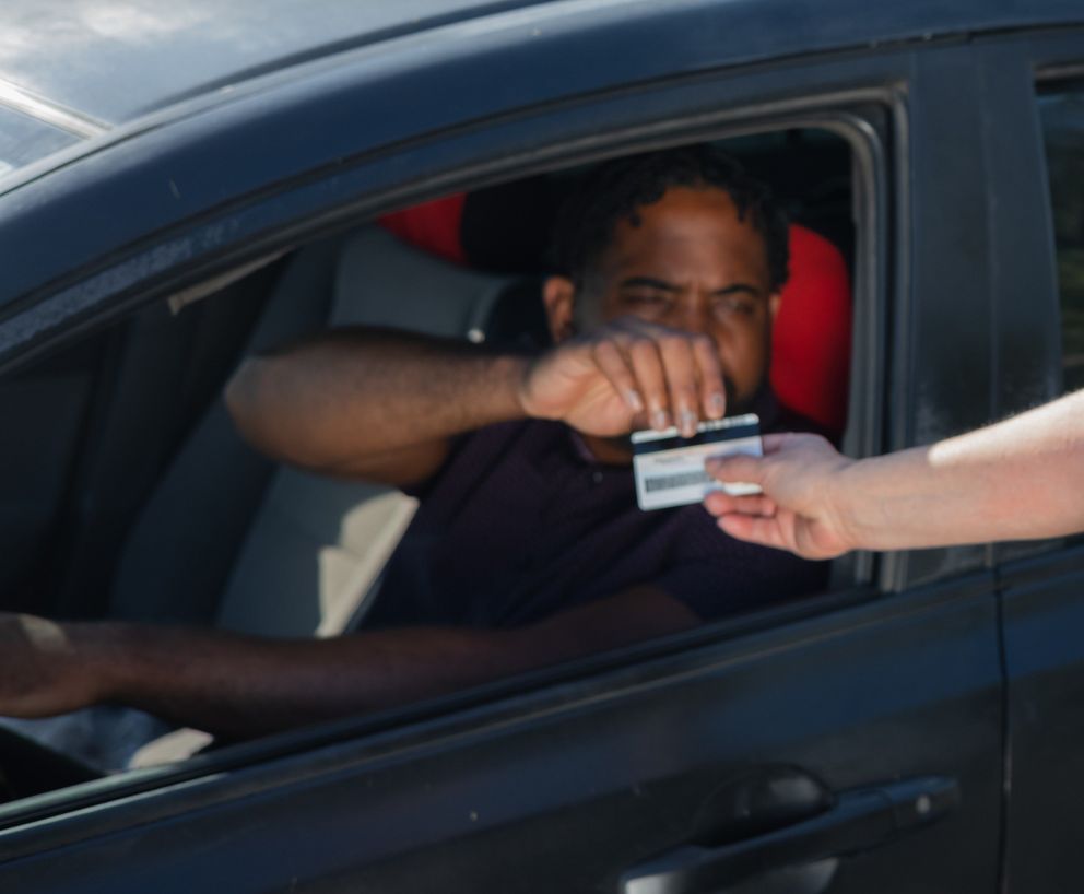 Un hombre dentro de un vehículo recibiendo una tarjeta. | Foto: Unsplash