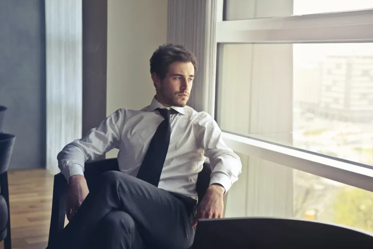Hombre sentado en una oficina mirando a través de la ventana. | Foto: Pexels