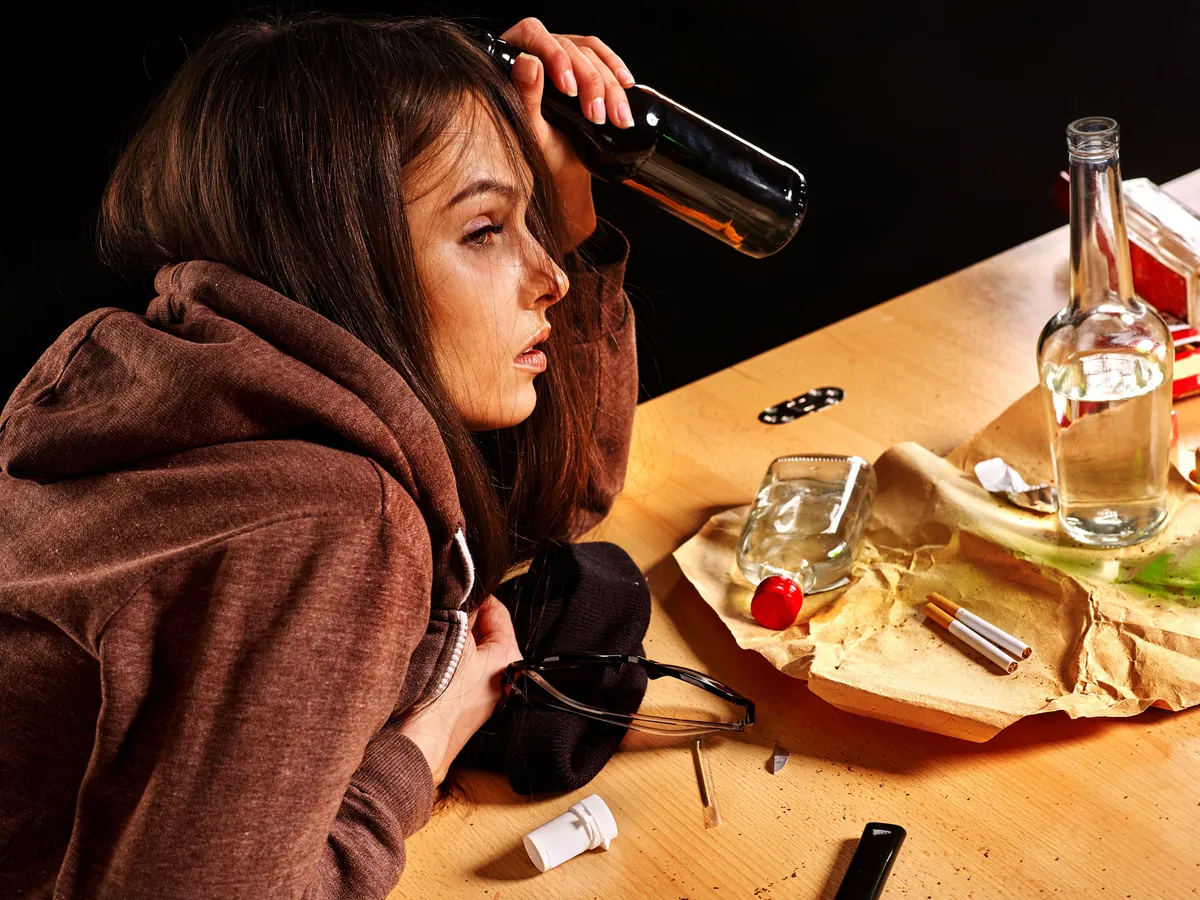 Une jeune femme avec des boissons alcoolisées et des cigarettes. | Photo : Shutterstock.