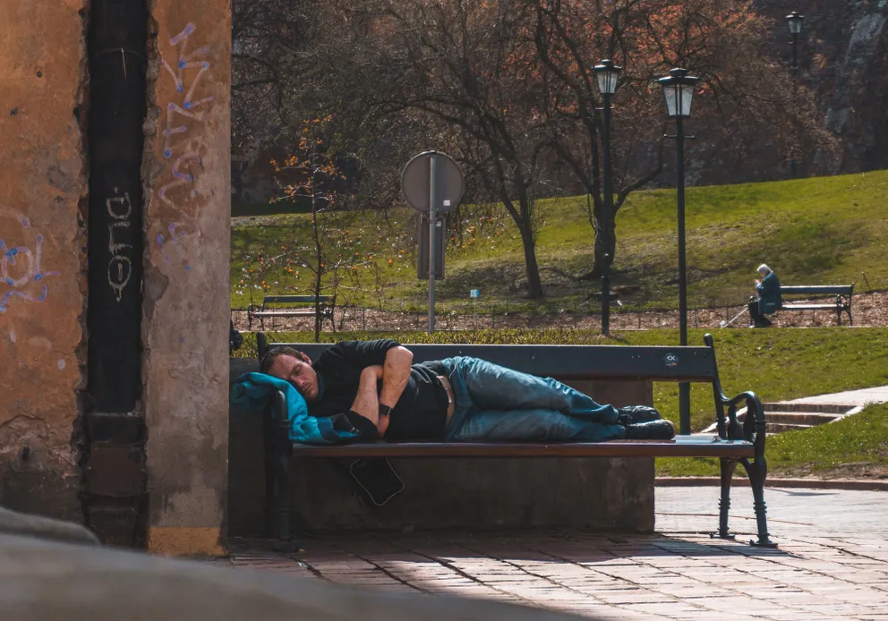 Un hombre durmiendo en el banquillo de un parque. | Foto: Unsplash