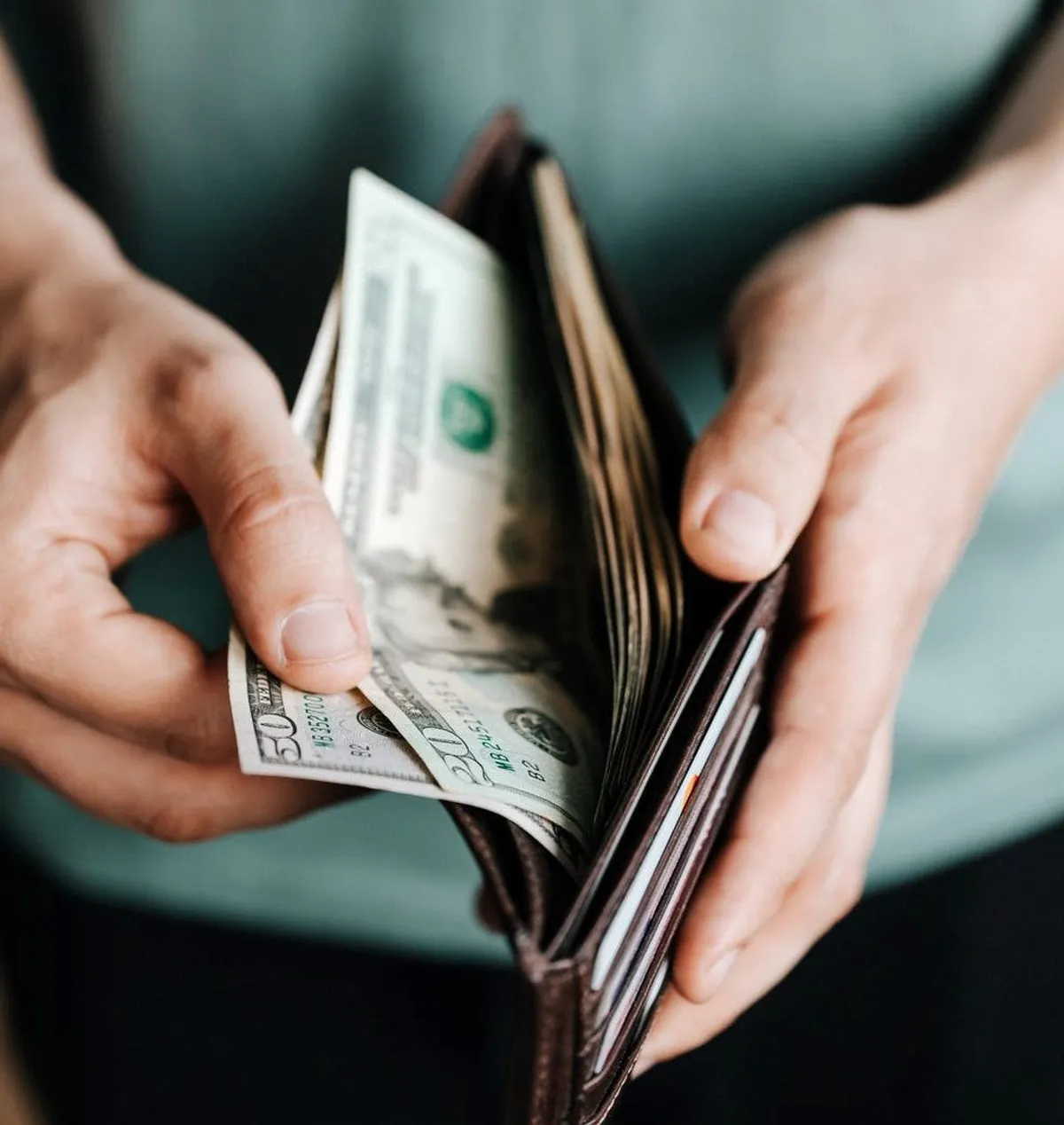 Hombre sosteniendo una billetera llena de dinero. | Foto: Pexels