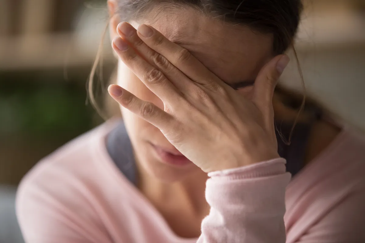 Une fille cache son visage derrière sa main. | Source : Shutterstock