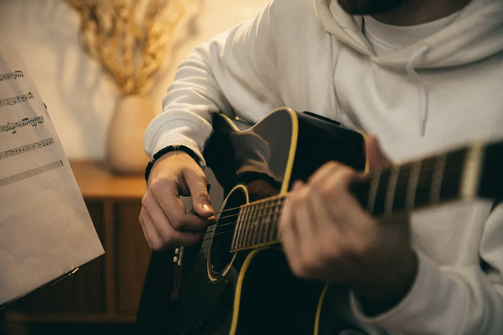 Un joven tocando una guitarra acústica. | Foto: Pexels