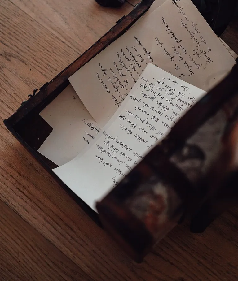 Varias hojas manuscritas en una caja. | Foto: Pexels