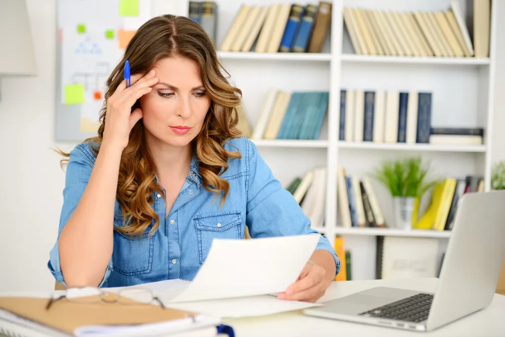 Mujer con cara de preocupación mientras revisa unos papeles. | Foto: Getty Images