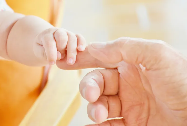 La mano de un bebé sosteniendo la mano de una persona adulta. | Foto: Pexels