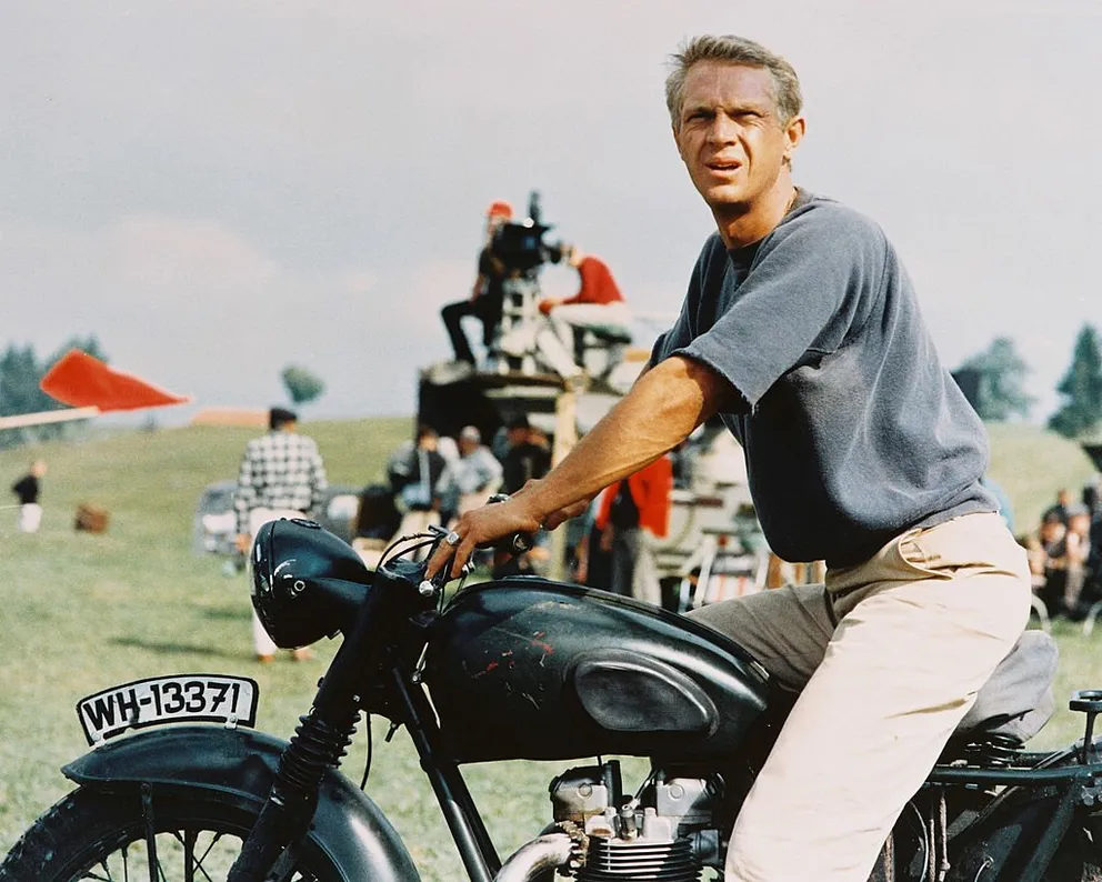 Steve McQueen assis à califourchon sur une moto dans une image publicitaire publiée pour le film "La Grande Évasion", en 1963. | Photo : Getty Images