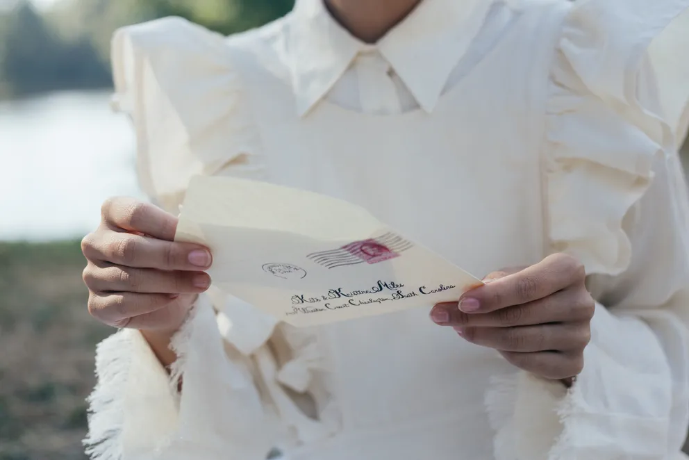 Una mujer abriendo un sobre para sacar una carta. | Foto: Pexels