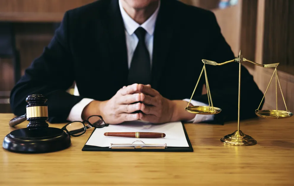 Un abogado sentado frente a su escritorio con unos documentos bajo sus manos. | Foto: Shutterstock