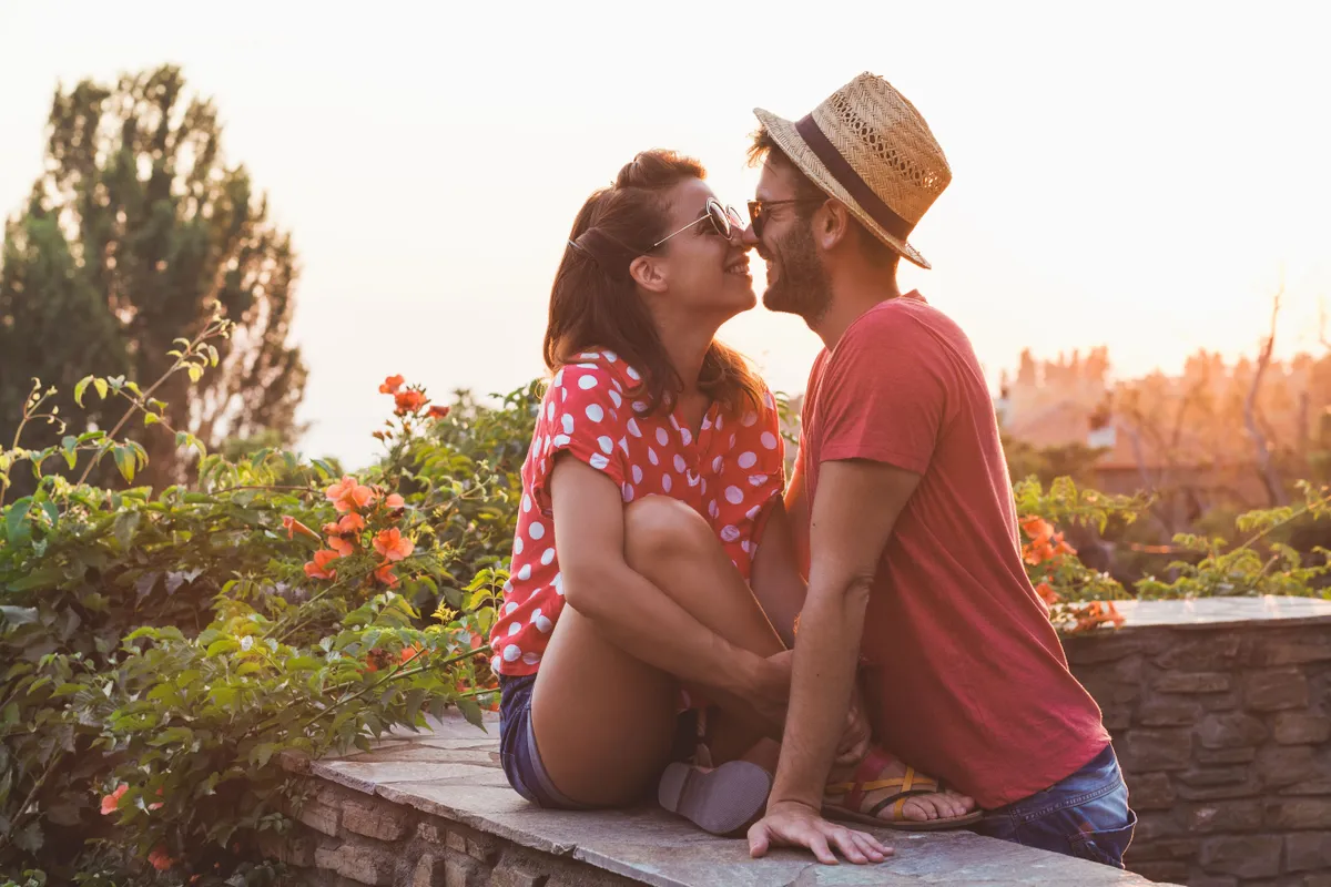 Ein glückliches Paar posiert während der goldenen Stunde auf seinem Balkon | Quelle: Shutterstock